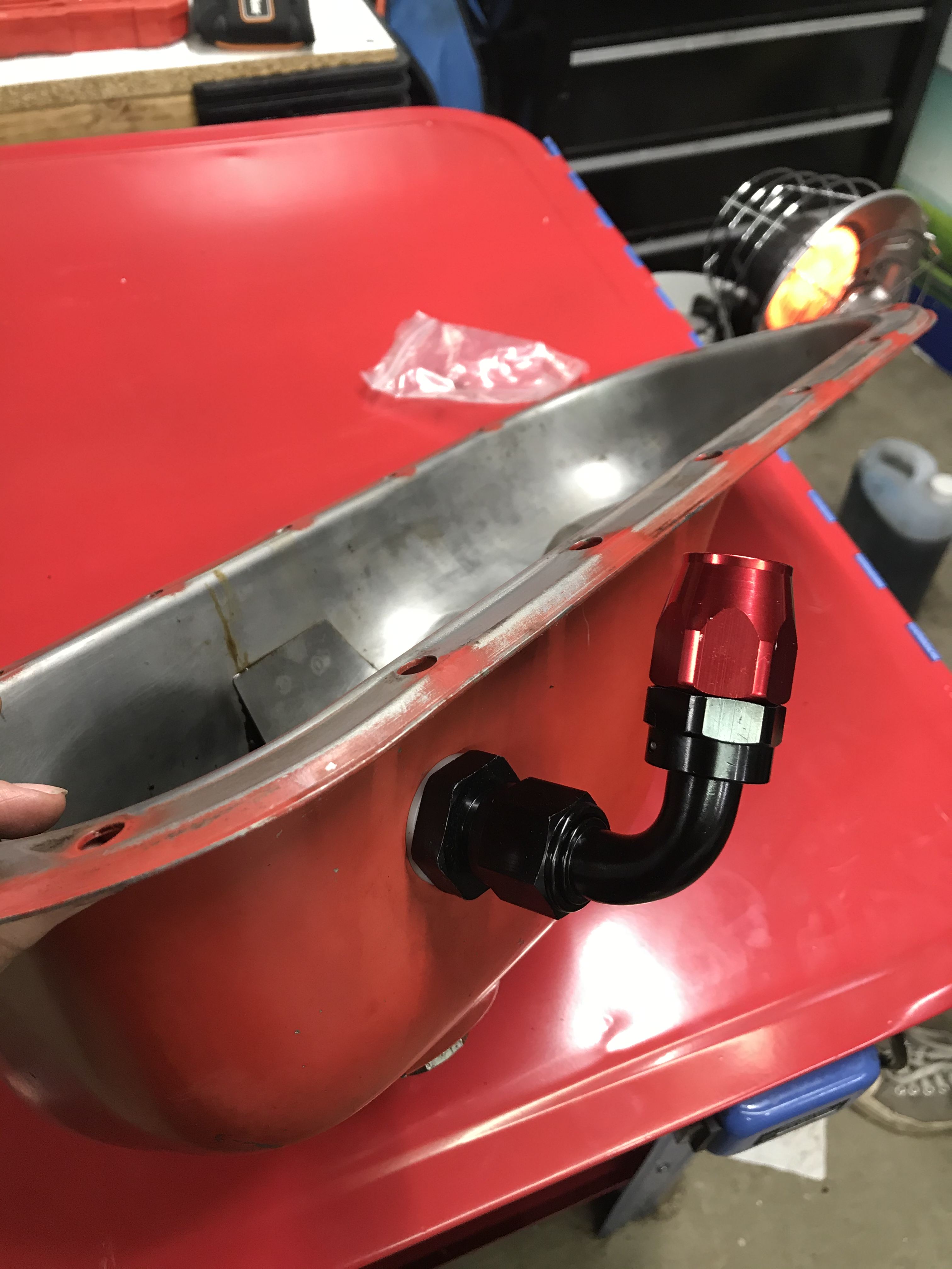 Red oil pan with AN right angle fitting installed in the side