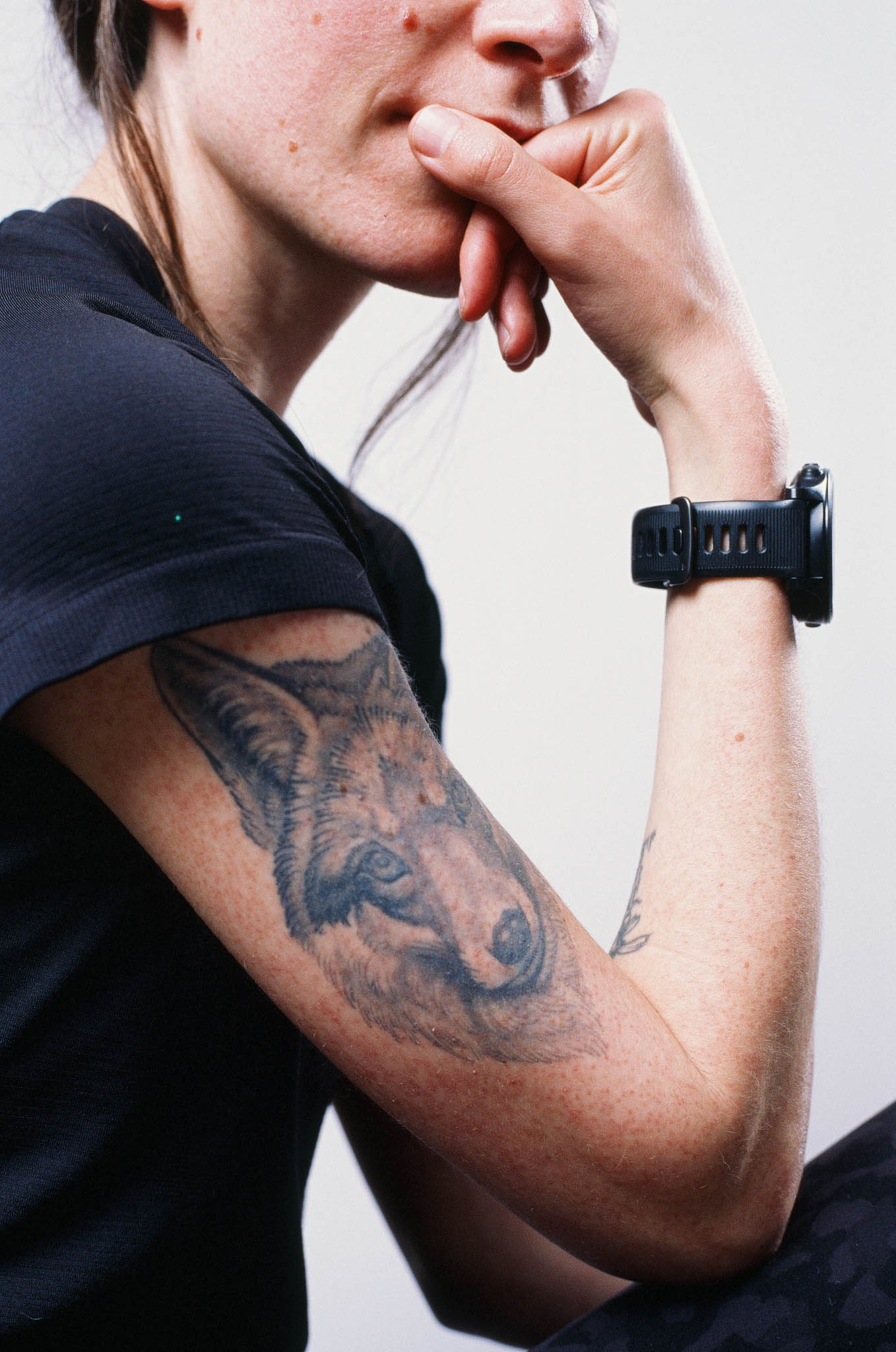 Color image of a woman with a tattooed arm on a white backdrop