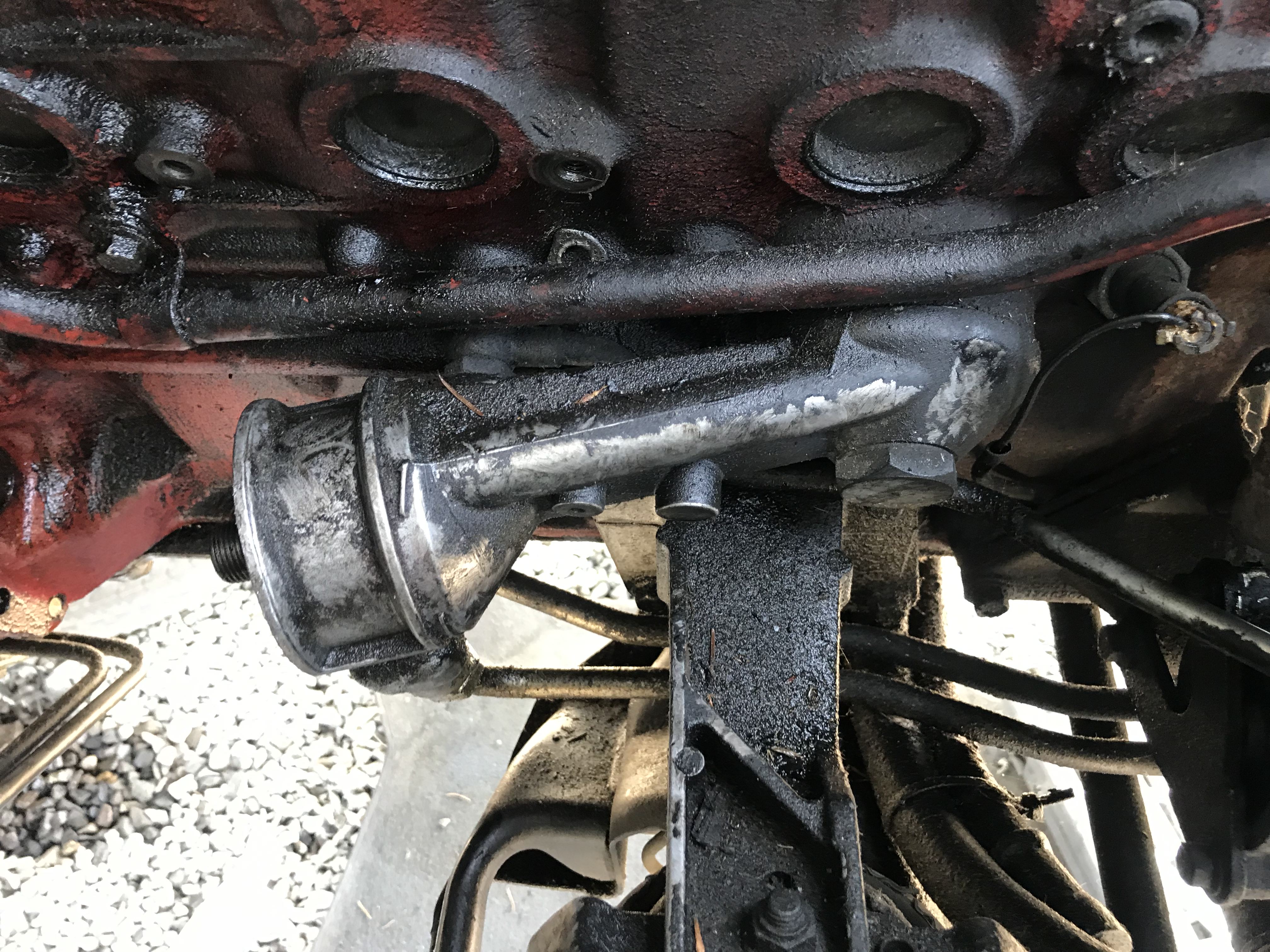 Water cooling adapter covered with grime attached to a red engine block