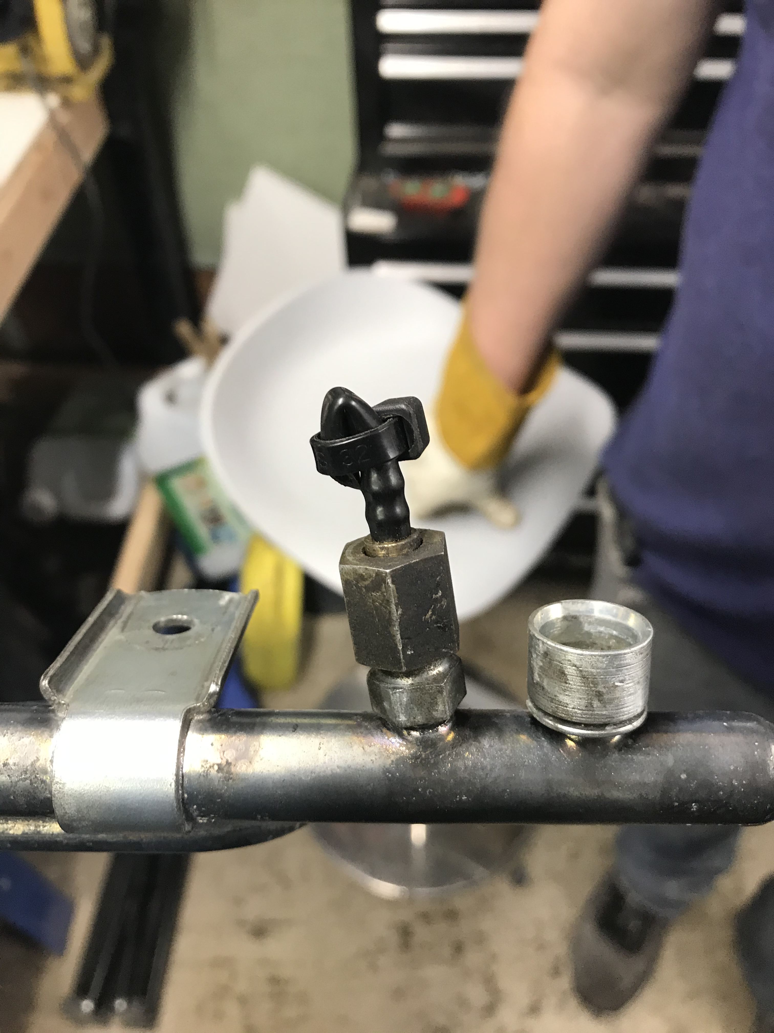 Metal fitting with black plastic hose folded back and secured with a ziptie